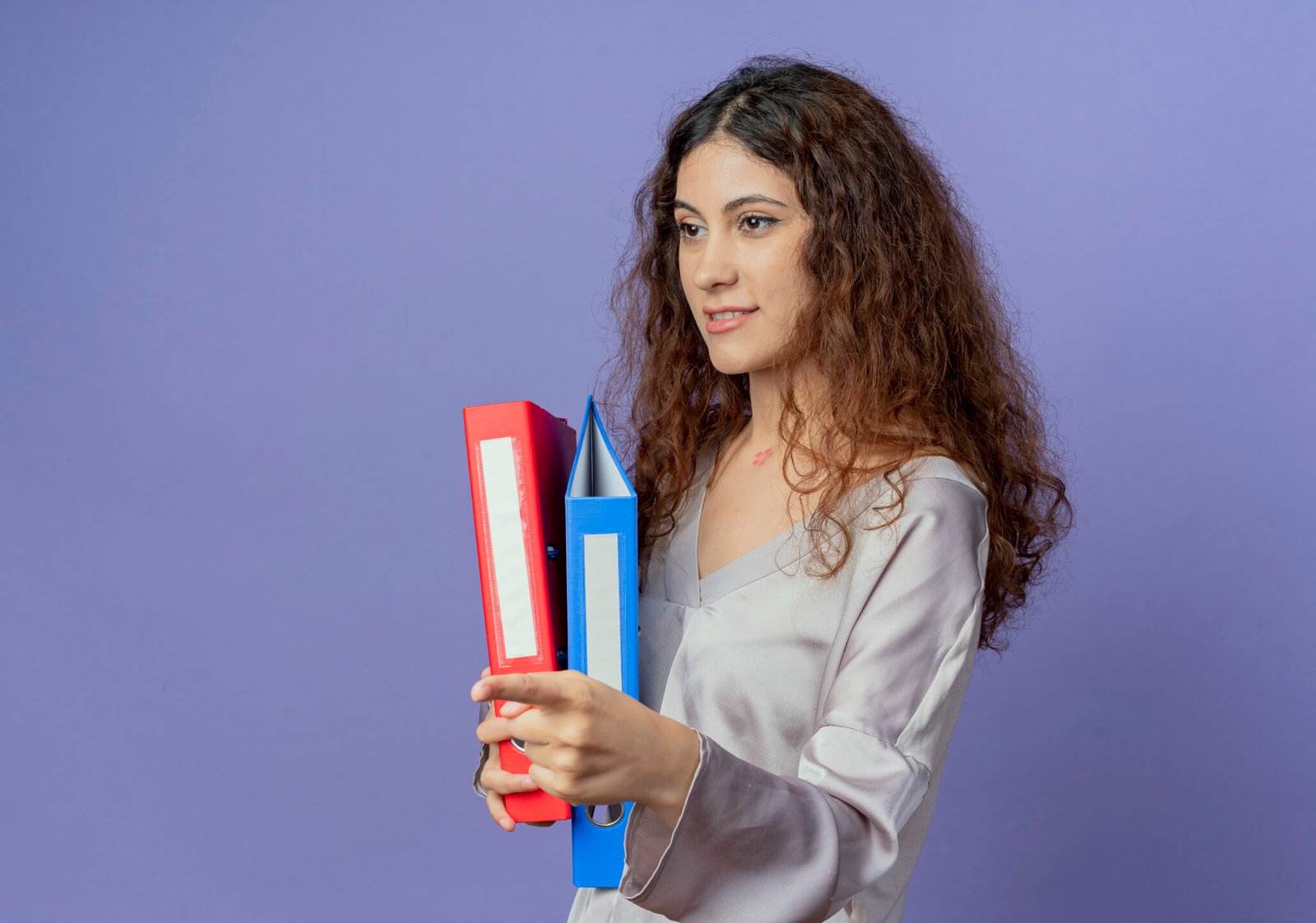 looking at side pleased young pretty girl holding folders isolated on blue background